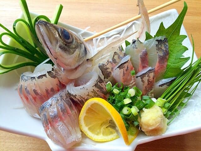 aji plated with lemon and green onions